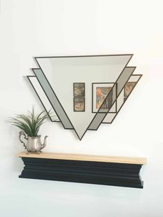 a mirror hanging on the wall above a shelf with a potted plant next to it