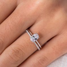 a woman's hand with a diamond ring on her left hand and the other hand holding an engagement ring