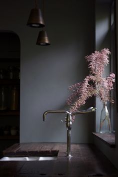 a vase filled with pink flowers sitting on top of a counter next to a window