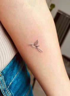 a small bird tattoo on the left upper arm and lower arm, with an arrow in the middle