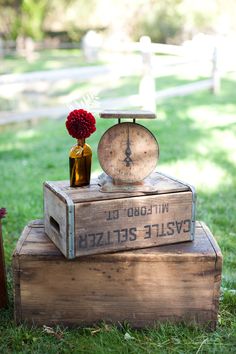 a wooden box with an old scale and flower in it sitting on top of other boxes