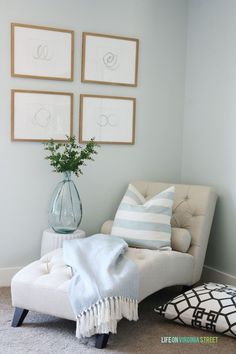 a living room with pictures on the wall and a white chair in front of it