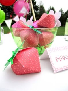 a bowl filled with strawberries sitting on top of a table next to a sign