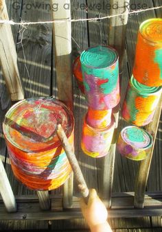 there are many different colored cans on the wooden deck with clothes pins attached to it