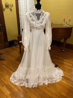 a white wedding dress on display in a room with wood flooring and yellow walls