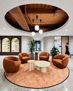 an office lobby with chairs, tables and plants in the center on a circular rug