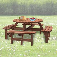 a picnic table with two benches and a bowl of fruit on it in the grass