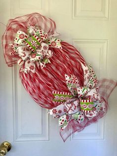 a red and white wreath hanging on the front door with christmas decorations attached to it