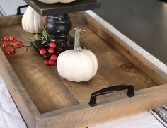 a wooden tray with some white pumpkins and other decorations on it, along with red berries