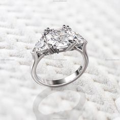 a three stone diamond ring sitting on top of a bed