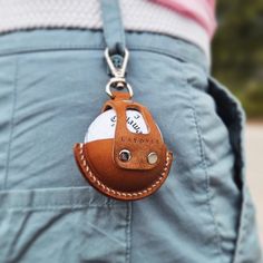 a person wearing a brown leather keychain with a white ball in the pocket