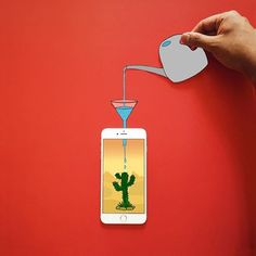 a hand is pouring liquid from a bottle into an iphone with a cactus on the screen