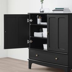 a black cabinet with two doors and drawers on the bottom shelf is next to a white wall