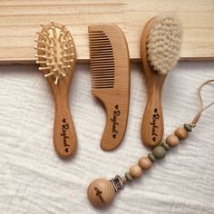 three wooden combs are sitting next to each other on a white sheet with beads