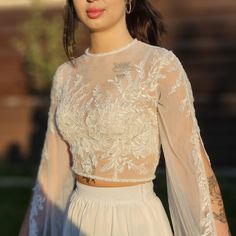 a woman wearing a white dress with sheer sleeves