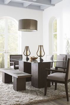 a dining room table with two chairs and a bench in front of the table is surrounded by rugs