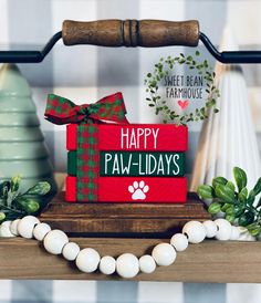 a red box that says happy paw - holidays with a green bow on it sitting on a wooden table