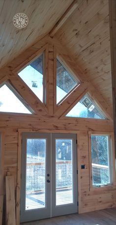 the inside of a wooden house with double doors and windows on each side of the door