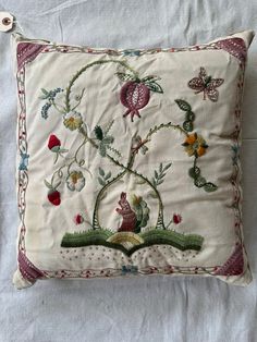 an embroidered pillow with flowers and birds on it