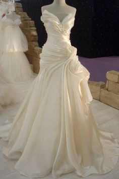 a white wedding dress on display at a bridal event with other gowns in the background