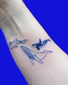 a hand with a tattoo on it that has two dolphins and an orca whale