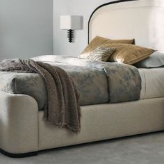 With a subtle nod to the grandeur of Art Deco, this upholstered bed introduces a harmonious mix of neutral hues, textures, and materials. It features an arched headboard accentuated with Sun-kissed Silver raffia, trimmed in Deep Bronze and wood banding in a Seal Skin finish. Elevated on a wood plinth base, its side rails and gently curving footboard are fully upholstered in an inviting, ivory textured woven. Rattan Bed, Arched Headboard, Cal King Bedding, Beige Bed, Bed Bench, Linen Upholstery, Grey Bedding, Upholstered Bed, King Bed