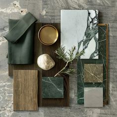 an assortment of marble and wood materials on a wooden table with green napkins, gold platedware, and other items