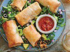 a blue plate topped with taquita filled pastries next to a bowl of salsa