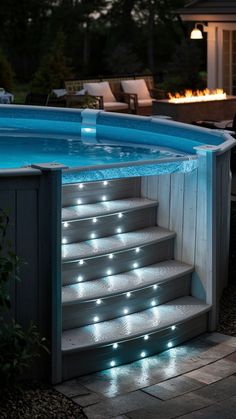 an above ground swimming pool with steps lit up and lights on the side, in front of a house