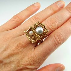 A custom made artisan ring in solid 14K yellow gold and set with two baroque salt water pearls. This ring dates to the 1970s and is in lovely condition ready to gift or to wear. The design is one of a kind and it is completely handmade with no cast or machined components. It is a big ring with the top of the ring measuring 13/16" long by 11/16" wide by 9/16" tall (21mm x 18mm x 15mm). In total it weighs 9 grams. On the inside of the shank is clearly marked 585 for 14K gold and also signed by the Heirloom Style Gold Pearl Open Ring, Heirloom Gold Pearl Open Ring, Unique 14k Yellow Gold Pearl Ring, Unique Yellow Gold Pearl Ring For Anniversary, Unique Gold Pearl Ring For Formal Occasions, Pearl Gold Ring, Brutalist Jewelry, Pearl Cocktail Ring, Pearl Anniversary