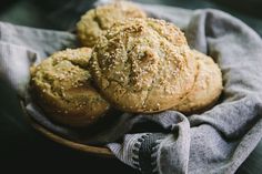 three muffins in a wooden bowl on a cloth