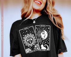 a woman wearing a black t - shirt with two tarot cards on it