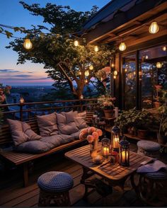 an outdoor seating area with candles and flowers on the table in front of it at night