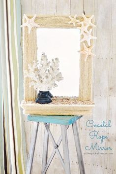 a small wooden table with a mirror and starfish decoration on it, next to a striped curtain