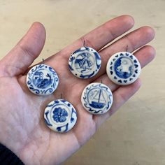 five blue and white porcelain buttons in the palm of someone's hand