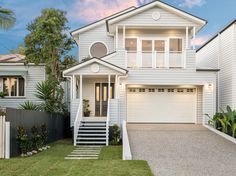 a white two story house with stairs leading up to the front door