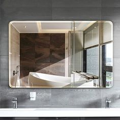 a bathroom with a large mirror on the wall and a bathtub in front of it