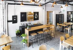 an empty restaurant with wooden tables and stools in front of the counter, surrounded by hanging lights