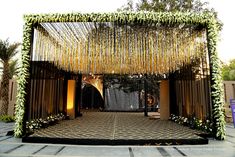 an entrance to a wedding venue decorated in gold and white flowers with greenery hanging from the ceiling