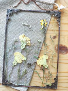 dried flowers are displayed in an old frame on a wooden table with fabric and wire