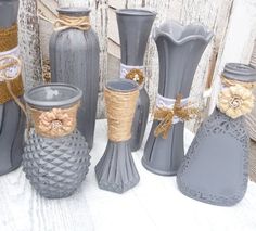 several gray vases with burlocks and twine tied around them on a table