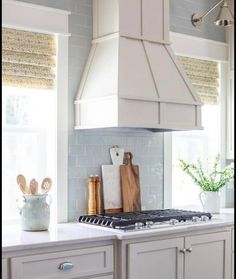 a kitchen with white cabinets and blue backsplash tiles on the countertops, along with wooden utensils