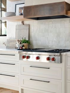 a stove top oven sitting inside of a kitchen next to white cabinets and counter tops