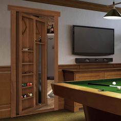 a pool table in a room with a television on the wall and an entertainment center behind it