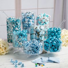 blue and white candies in glass containers on table next to flower arrangement with scissors