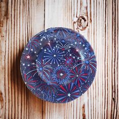 a blue plate with red, white and blue fireworks on it sitting on a wooden surface