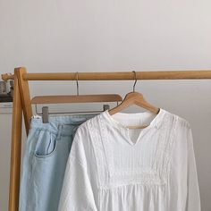 two shirts hanging on a clothes rack in front of a white shirt and blue jeans