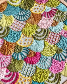 a close up of an embroidered object on a wooden table cloth with colorful designs and colors