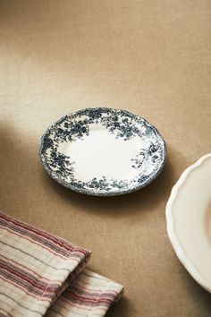 an empty plate sitting on top of a table next to a bowl and saucer