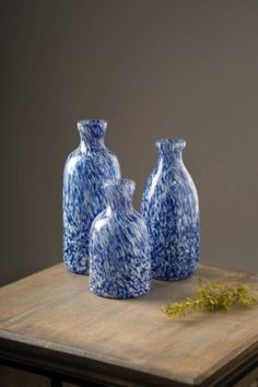 three blue and white vases sitting on top of a wooden table next to each other